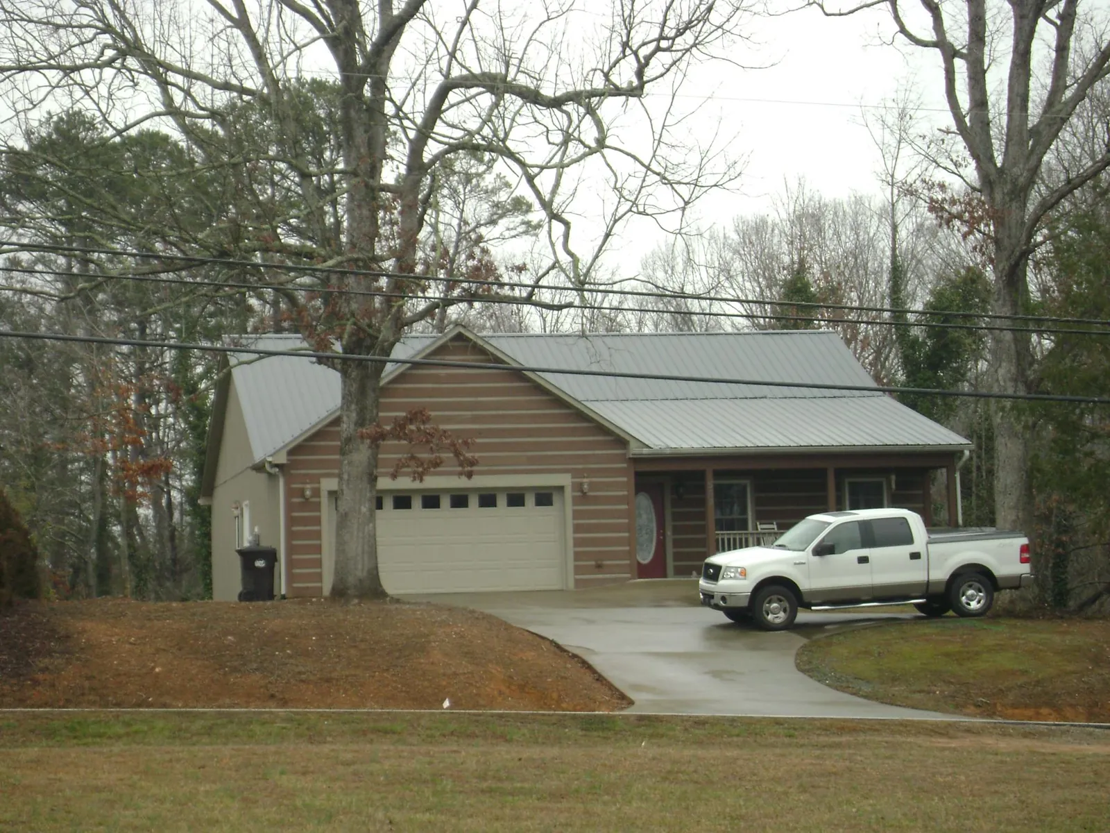 Gray metal roof on a log sided house with an attached two car garage in Riverdale